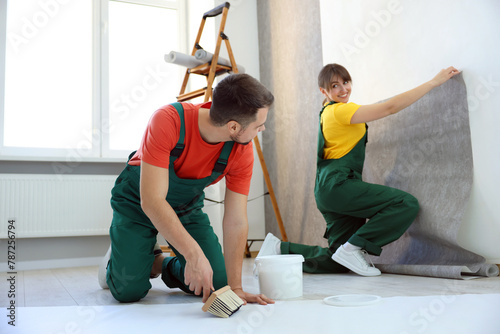 Workers hanging stylish gray wallpaper in room