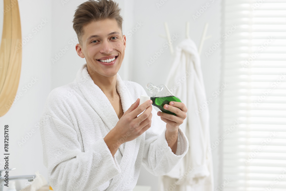 Young man with mouthwash in bathroom. Oral hygiene Young man with mouthwash in bathroom. Oral hygiene