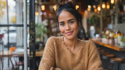 Charming young woman smiling at cozy cafe, vibrant autumn colors, casual style, leisure theme, reminiscent of Thanksgiving gatherings and friendly reunions. photo