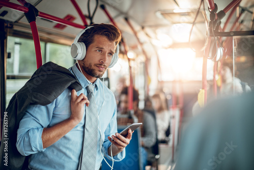 Businessman listening to music on headphones while commuting by bus photo