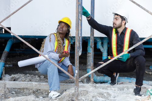Construction civil engineer man and woman African American checking quality water pipes inside building of work in construction site.