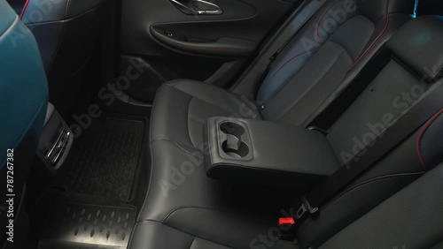 The camera slowly moves around the black interior of a premium car. View of the rear seats