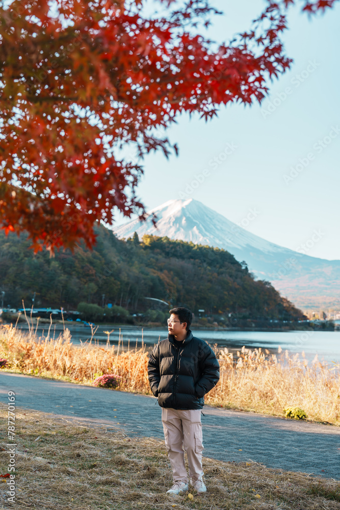 man tourist with Fuji Mountain at Lake Kawaguchi in Autumn season, happy Traveler travel Mount Fuji, Yamanashi, Japan. Landmark for tourists attraction. Japan Travel, Destination and Vacation