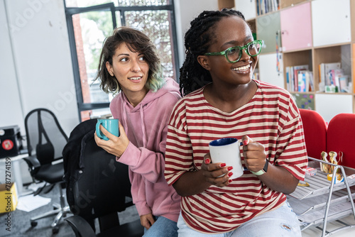 In student support office, a two female student joying in a coffee break, a beacon of empowerment and knowledge, ready to conquer academic challenges and embrace her future.	
