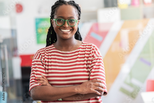 In her student support office, a determined black female student stands confidently.
