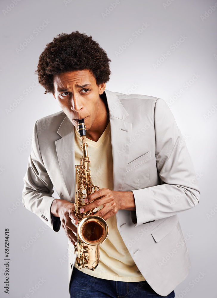 Fototapeta premium Happy, african man and music, playing the saxophone with casual outfit and clothing in studio. Confident musician, jazz and instrument with trendy suit for band performance on white background