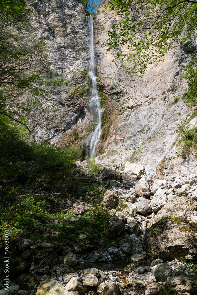 Brinta Waterfall hidden inside the forest, beauties of Slovenia to be discovered. Near Nova Gorica, Tolmin village. Water spray, vivid rainbow forms from the waterfall that falls sheer onto the rock.