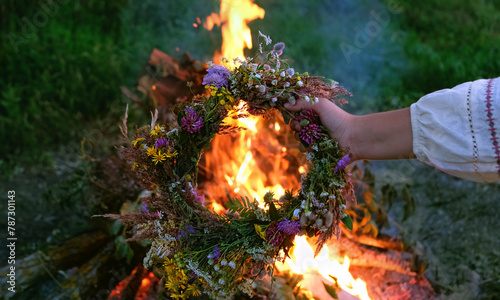 Quadro su tela Women's hand hold floral wreath against bonfire, abstract natural background