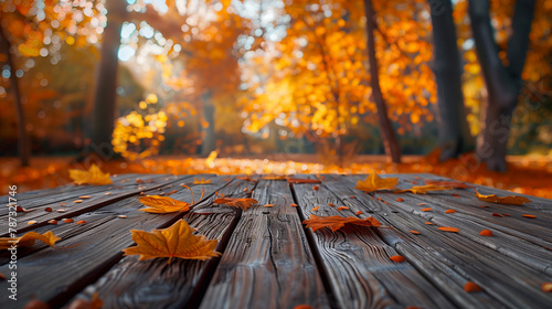 Wooden table in autumn park with fallen leaves and bokeh