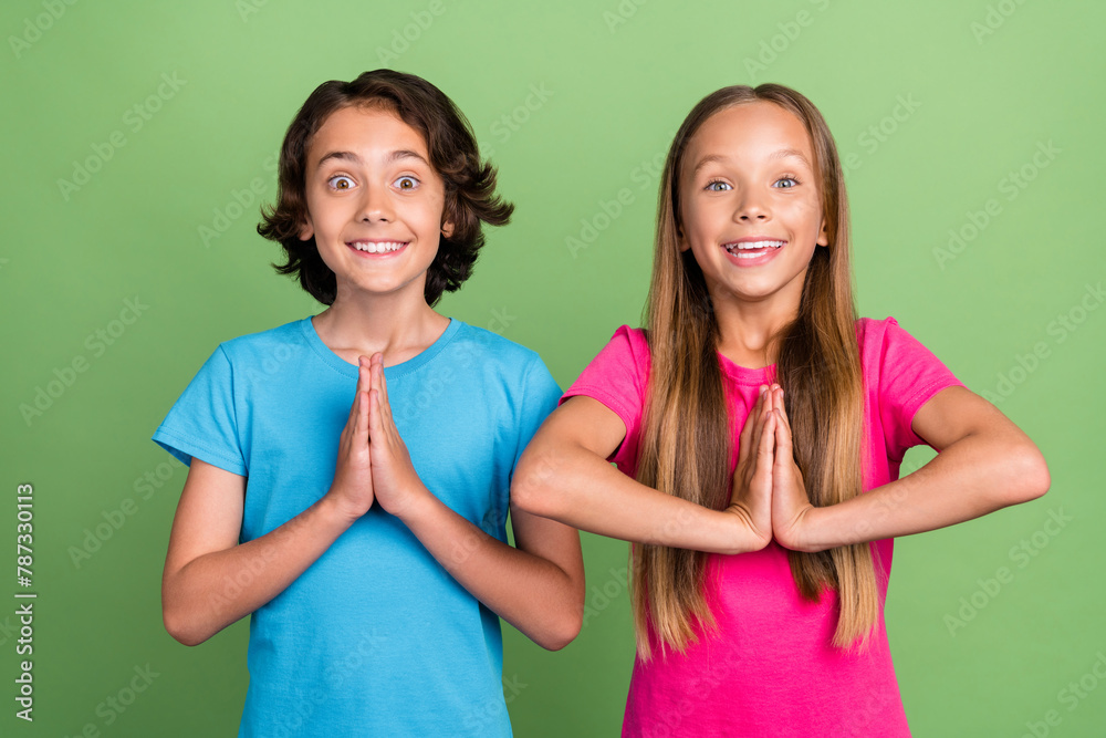 Photo of charming excited friends wear t-shirts arms togher praying isolated green color background - obrazy, fototapety, plakaty 