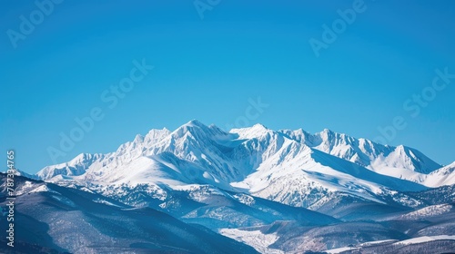 Fresh snow covering the peaks of mountains under a clear blue sky