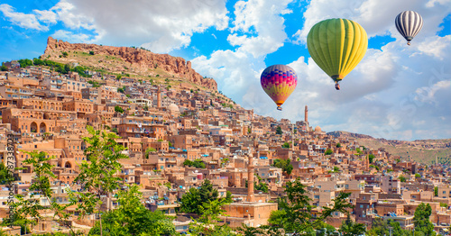 Hot air balloon flying over Mardin old town with bright blue sky - Mardin, Turkey
