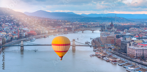 Hot air balloon flying over Hungarian parliament and Chain Bridge at sunset in Budapest 