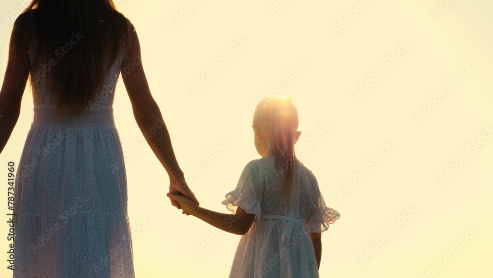Family mother and daughter walking outdoor bright sun sky nature landscape enjoy freedom closeup back view. Elegant woman and girl kid in white dress going holding hands at sunlight sunset sunrise - obrazy, fototapety, plakaty 