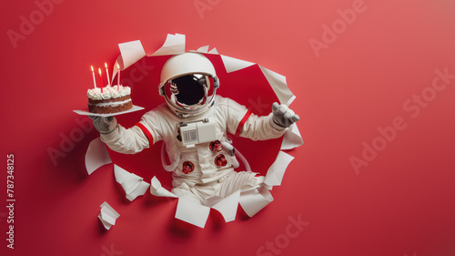 In the excitement of celebration, an astronaut delightfully presents a two-layered cake with candles on a vibrant red space