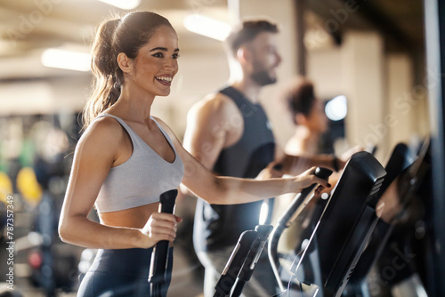 Fit happy sportswoman is exercising with her friends on synchro machine in a gym.