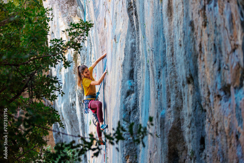 The girl climbs the rock. The climber trains on natural terrain. Extreme sport. A woman overcomes a difficult route rock climbing..