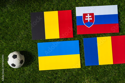 Belgium Leads Group E: Flags of Belgium, Slovakia, Romania, Ukraine, and soccer ball on green grass at Europe football tournament in Germany in 2024