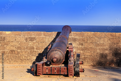 Beautiful blue sky and look like old time. movable sixteenth century Portuguese cannon made of metal and a wooden base. It's located on a bastion of Diu Fort, a tourist spot located in Diu India.j photo