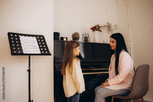 Vocal lesson. Girl in blue dress and her teacher doing voice exercises photo