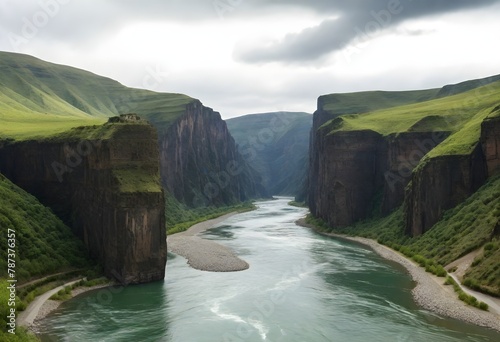 A river flowing through a green canyon with steep cliffs under a cloudy sky