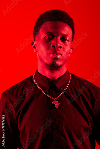 A black man standing confidently in front of a vibrant red background in a studio setting.