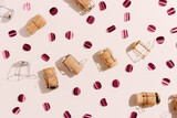 Champagne corks and sparkling confetti, top view composition, holidays, celebration concept. Wooden cork and muselet on pastel background at sunlight shadows. Flat lay festive minimal pattern