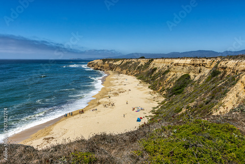 Pacific ocean on sandy Cowell Ranch State beach surrounded by sea cliffs, rocky headlands on sunny day in San Mateo County, California