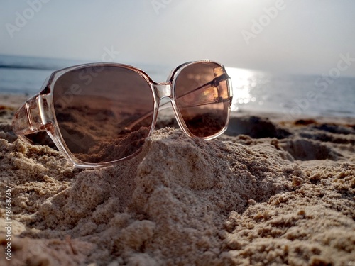 smartBrown sun glasses lie on the sand. April 15, 2024 Maroona Beach - Qatar 