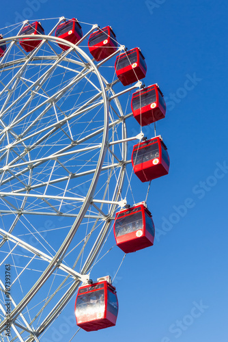 Colorful ferris wheel of the amusement park in the blue sky background.