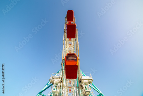 Colorful ferris wheel of the amusement park in the blue sky background.
