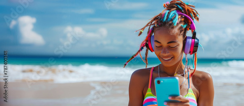 woman with colorful dreadlocks with headphones and phone on the beach