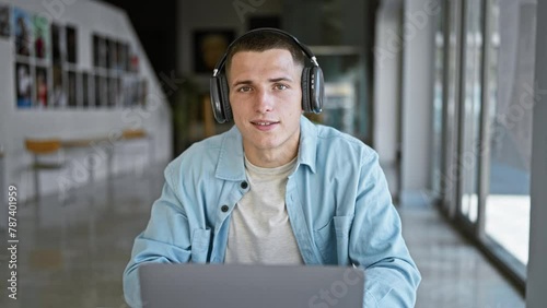 A focused young man with headphones using a laptop in a modern university interior. photo