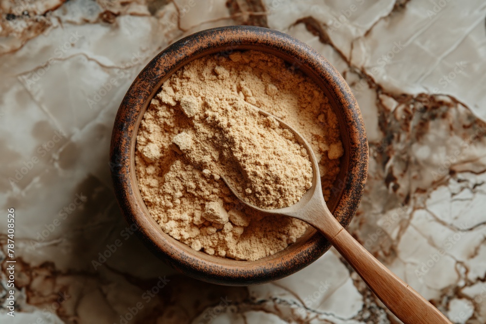 Maca powder in a wooden bowl with a spoon, set against a marble background Maca powder in a wooden bowl with a spoon, set against a marble background