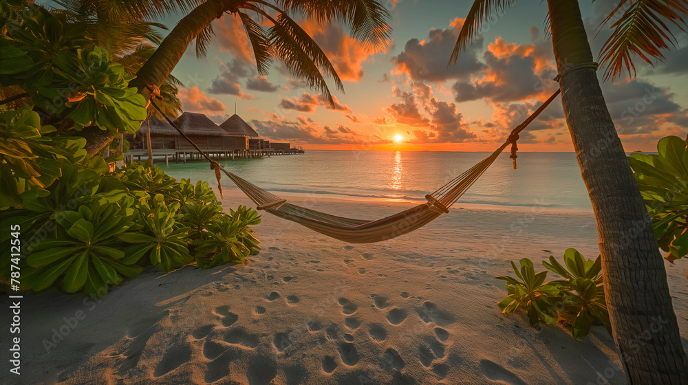 Hammock between two palm trees on the beach against the blue sea