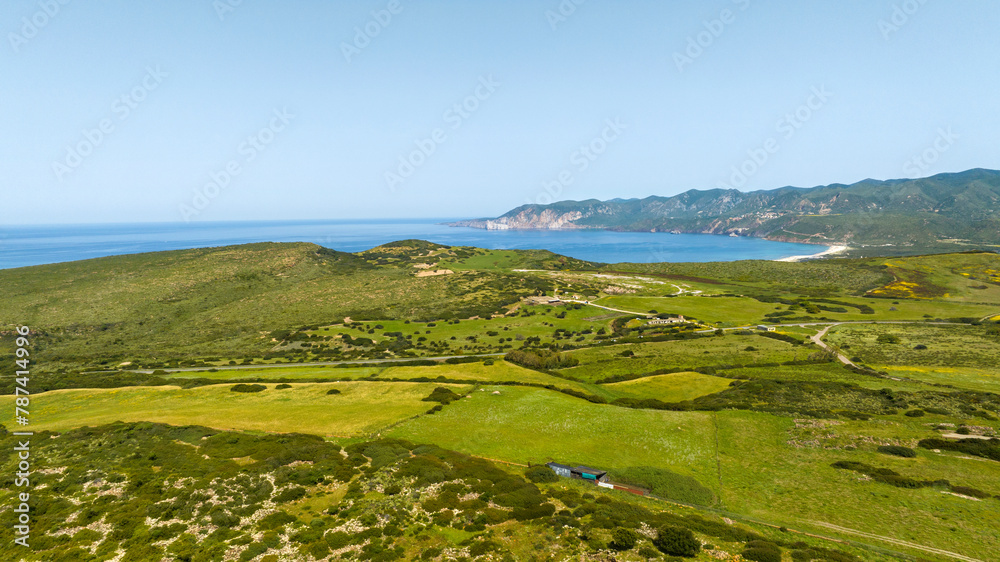 Aerial view of Plagemesu beach located in the municipality of Gonnesa, in southern Sardinia, Italy. The coast is characterized by hills that descend to the sea. Aerial view of Plagemesu beach located in the municipality of Gonnesa, in southern Sardinia, Italy. The coast is characterized by hills that descend to the sea.
