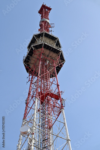 Red and white communication tower against blue sky photo