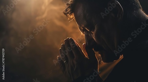 man praying with hands clasped in darkness spiritual devotion and faith photo