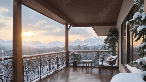 A view of snow-covered mountains from a wooden balcony with a table and two chairs.  