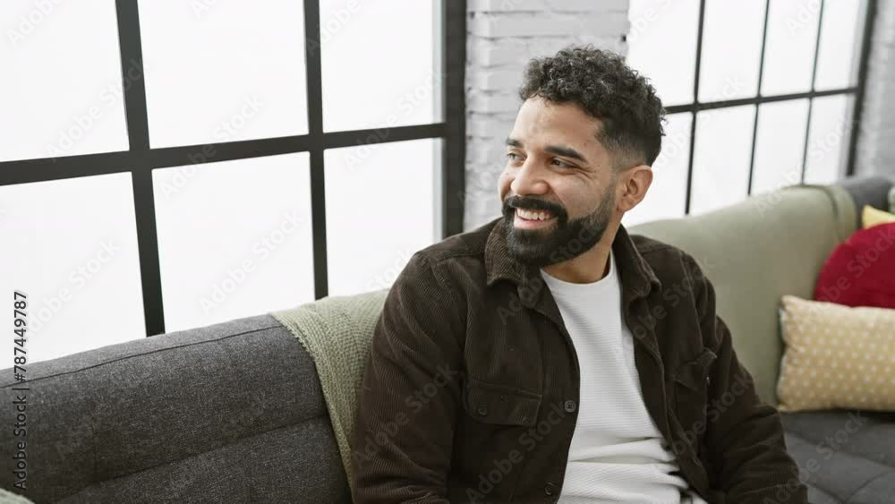Smiling young man confidently glances away with a natural laugh - a cheerful expression home, showcasing hispanic male's vibrant lifestyle Smiling young man confidently glances away with a natural laugh - a cheerful expression home, showcasing hispanic male's vibrant lifestyle