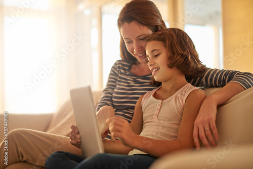 Mother, child and sofa with tablet for streaming movies, happiness and bonding together in living room. Family, mom and young girl with technology for e learning, education or social media in home © peopleimages.com