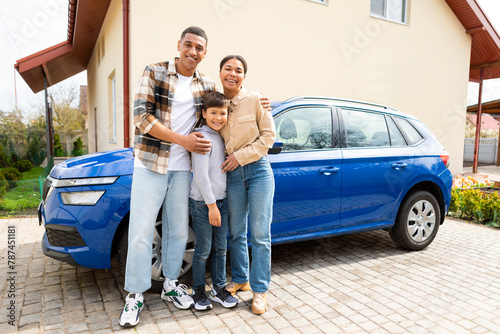 Happy family with their son arrived by car to their new home, posing and embracing. Renting and buying house photo