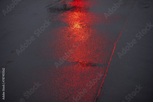 reflections of a red traffic light on wet asphalt in rainy weather in the evening