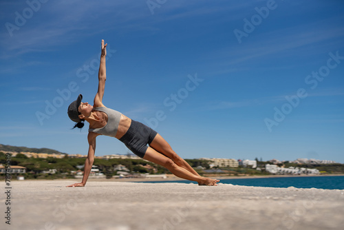 Sultry Brunette Athlete in Sportswear and Baseball Cap Training by the Sea