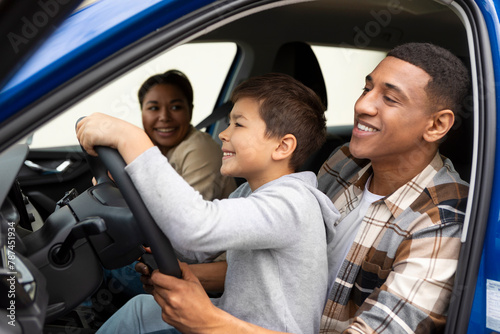 Excited preteen boy sitting on father lap, driving automobile together and smiling, enjoying their new car and family trip