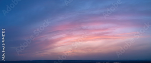 Ideal for Sky replacement project: Large Panoramic, pastel pink-orange-blue evening sky after sunset with soft clouds illuminated by orange sunset, aerial photography, far horizon without obstacles.