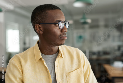Young African businessman deep in thought while standing in an office