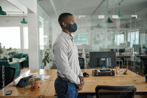 African businessman standing in an office wearing a face mask
