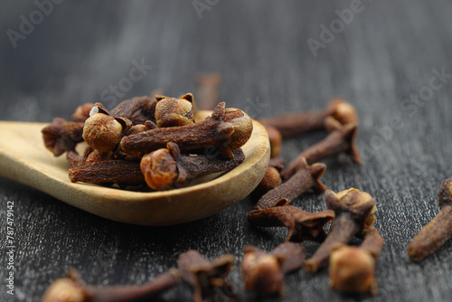 Dry cloves in wooden scoop isolated on white background with clipping path. Top view. Flat lay. selective focus. © bt1976