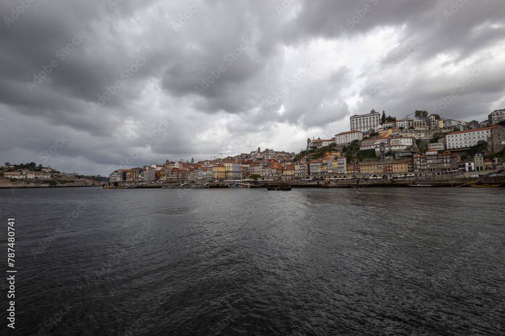 View of the north bank of the Duero River in Porto west of the Luis I Bridge from river level with wide angle objects - Bishop's Palace - cumulus clouds